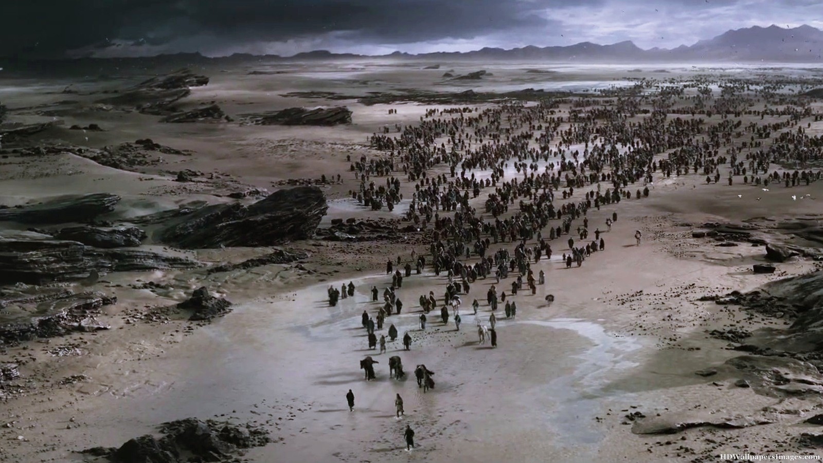 Hundreds of tiny figures of people walking across a barren landscape.