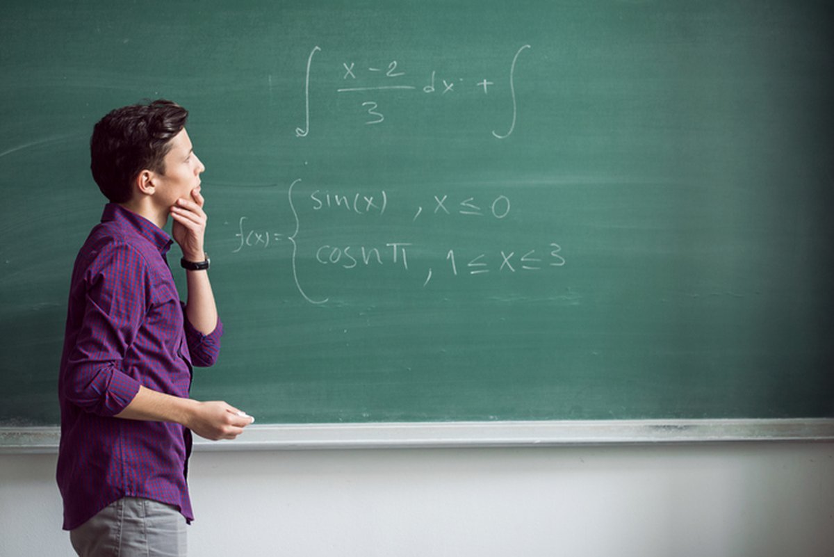 Young man looks at math symbols on a chalk board and wonders